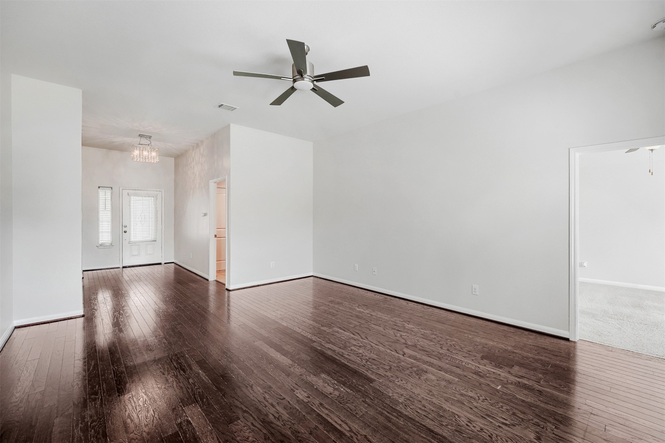 13408 Clara Martin Road Manor, TX 78653 - Photo 5 of 27 a view of a room with wooden floor a ceiling fan and windows