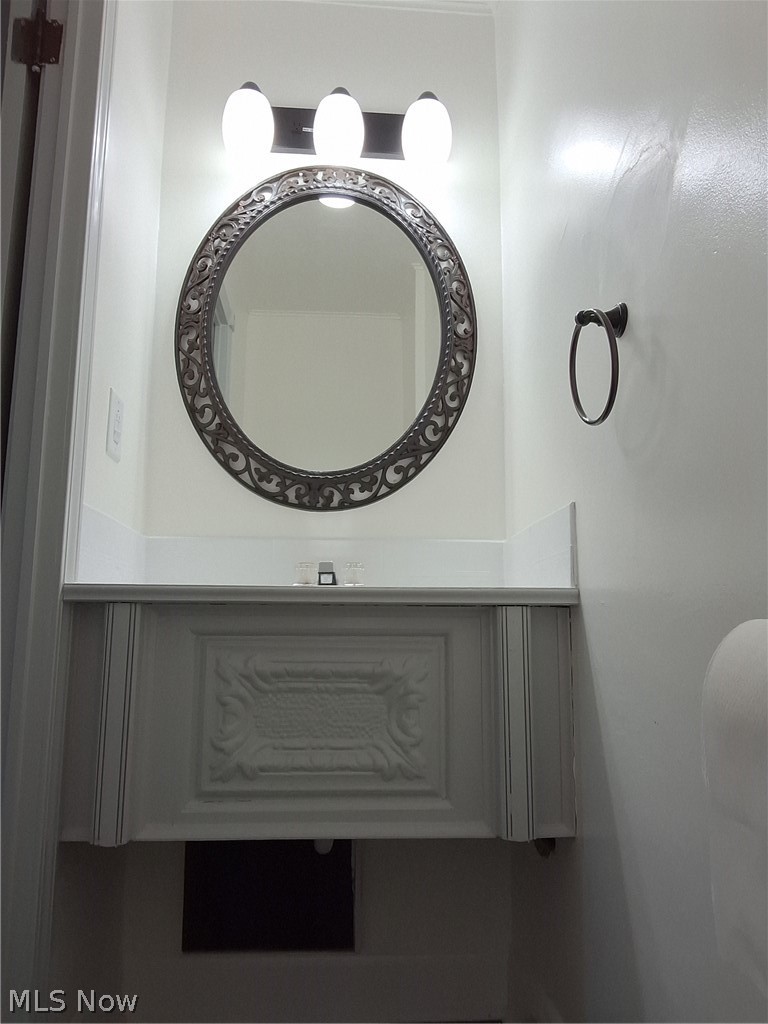 236 Bowland Road Mansfield, OH 44907 - Photo 22 of 34 Vanity area featuring a decorative round mirror, a three-light fixture, and a white vanity with carved paneling and a light-toned countertop