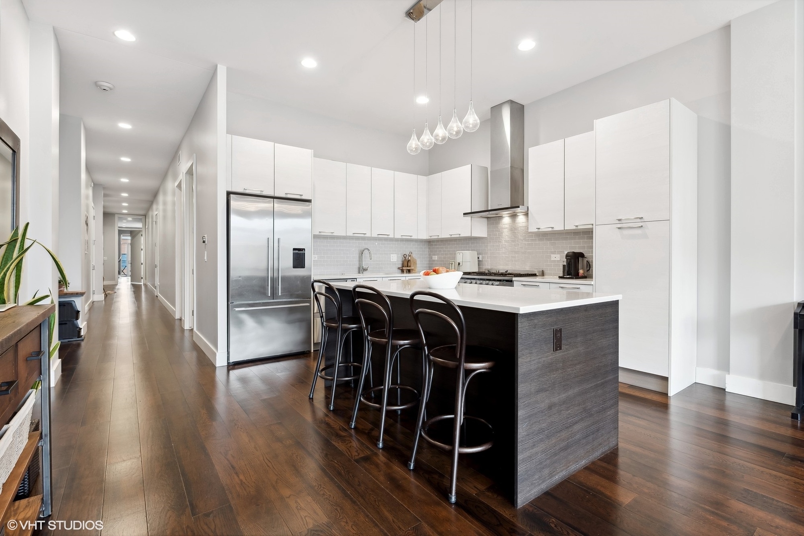 1120 West Adams Street, Unit 3E Chicago, IL 60607 - Photo 7 of 21 a kitchen with stainless steel appliances kitchen island granite countertop a refrigerator a stove a sink dishwasher and white cabinets with wooden floor