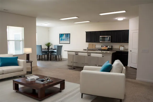 a living room with furniture kitchen view and a window