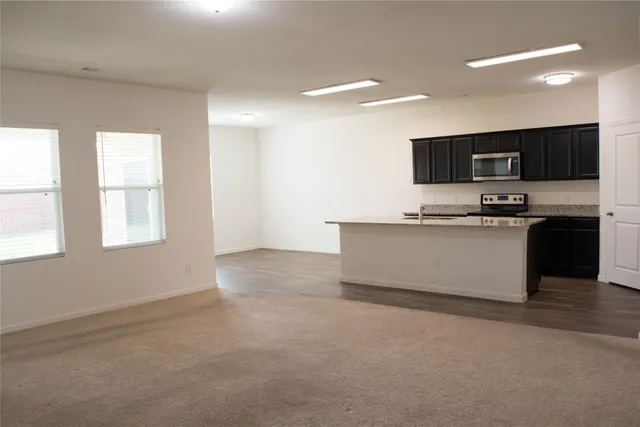 a large kitchen with stainless steel appliances kitchen island a large counter top a stove a sink and a refrigerator