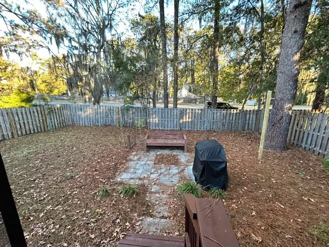 a view of a backyard with large trees and wooden fence