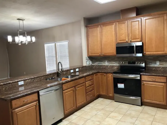 a kitchen with stainless steel appliances granite countertop a stove a sink and a microwave
