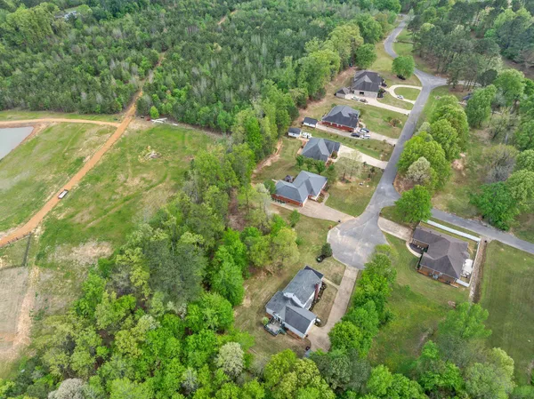 an aerial view of residential house with outdoor space and trees all around