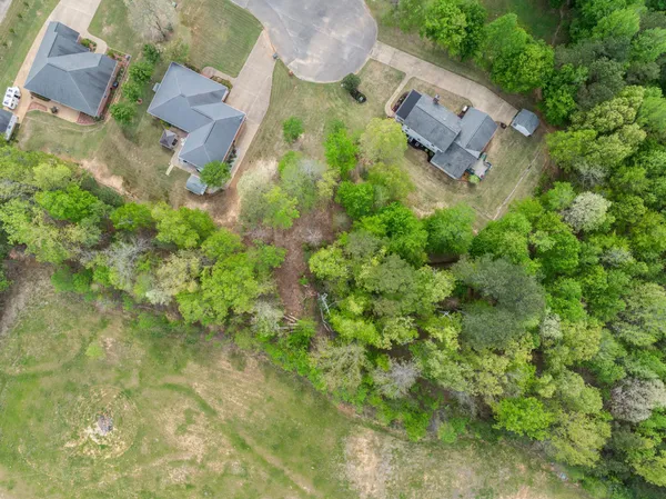an aerial view of residential house with outdoor space and trees all around
