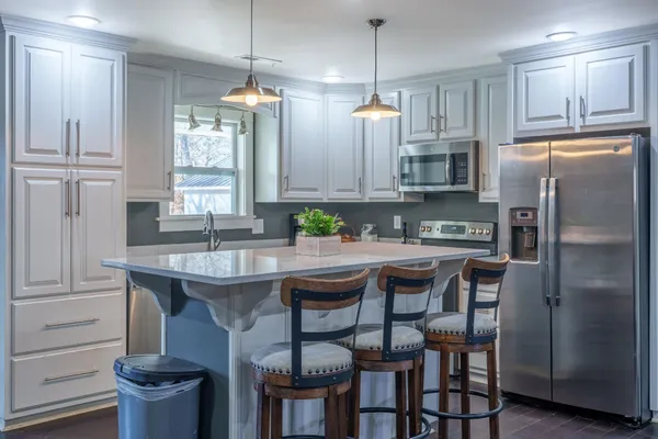 a kitchen with stainless steel appliances granite countertop a table chairs stove and refrigerator