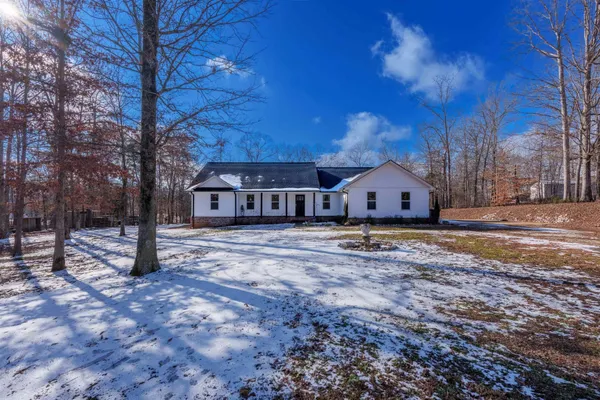 a kitchen with stainless steel appliances kitchen island granite countertop a sink dishwasher a stove and white cabinets with wooden floor