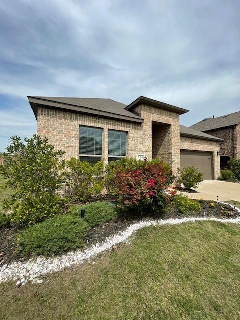 View of front of house featuring brick siding, a garage, concrete driveway, and a front yard