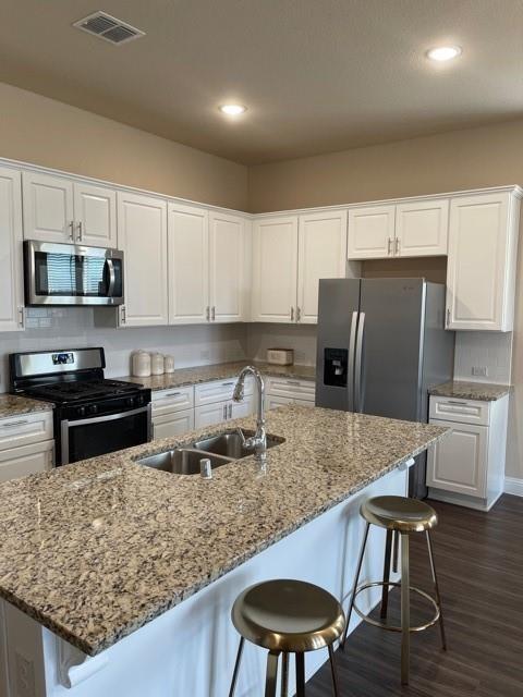 569 Spruce Trail Forney, TX 75126 - Photo 21 of 22 Kitchen with white cabinetry, a kitchen breakfast bar, stainless steel appliances, light stone counters, and recessed lighting