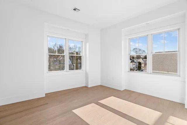 a view of a big room with wooden floor and windows