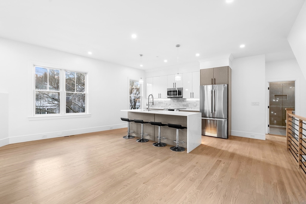 143 Tremont Street, Unit A Boston, MA 02135 - Photo 2 of 28 a kitchen with stainless steel appliances kitchen island hardwood floor sink and stove