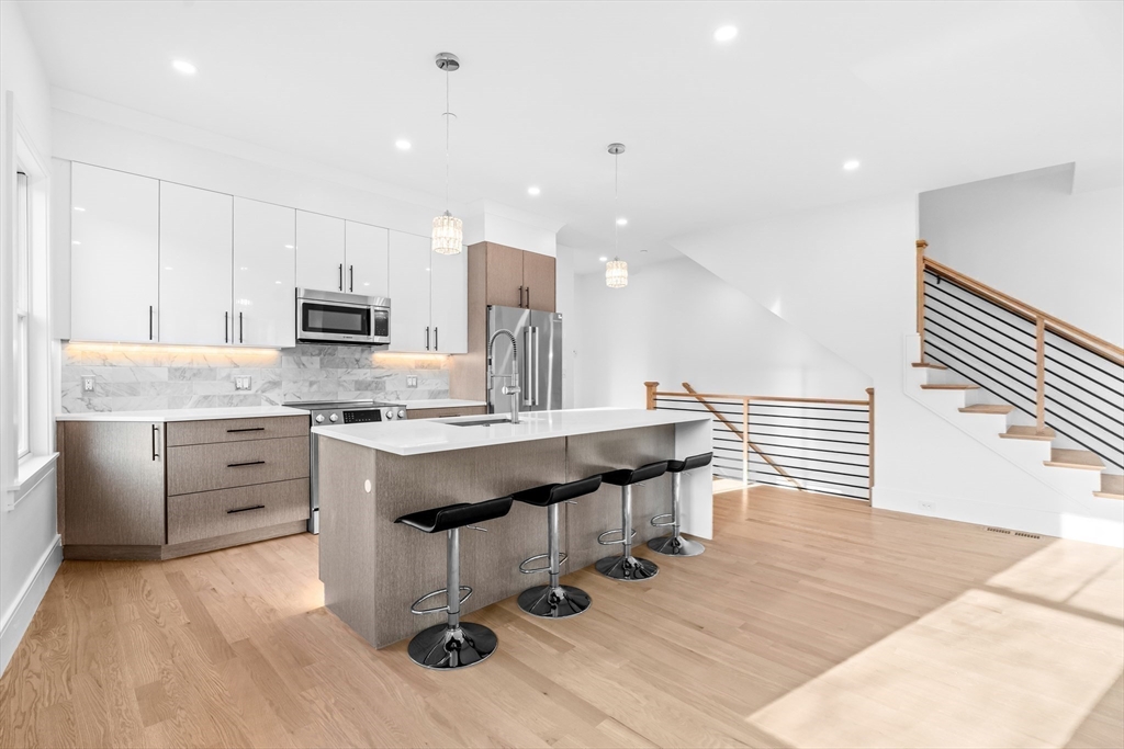 143 Tremont Street, Unit A Boston, MA 02135 - Photo 6 of 28 a kitchen with kitchen island granite countertop a sink counter top space appliances and cabinets