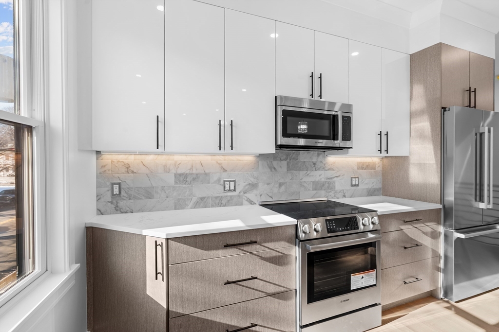 143 Tremont Street, Unit A Boston, MA 02135 - Photo 7 of 28 a kitchen with stainless steel appliances a stove a microwave and a sink