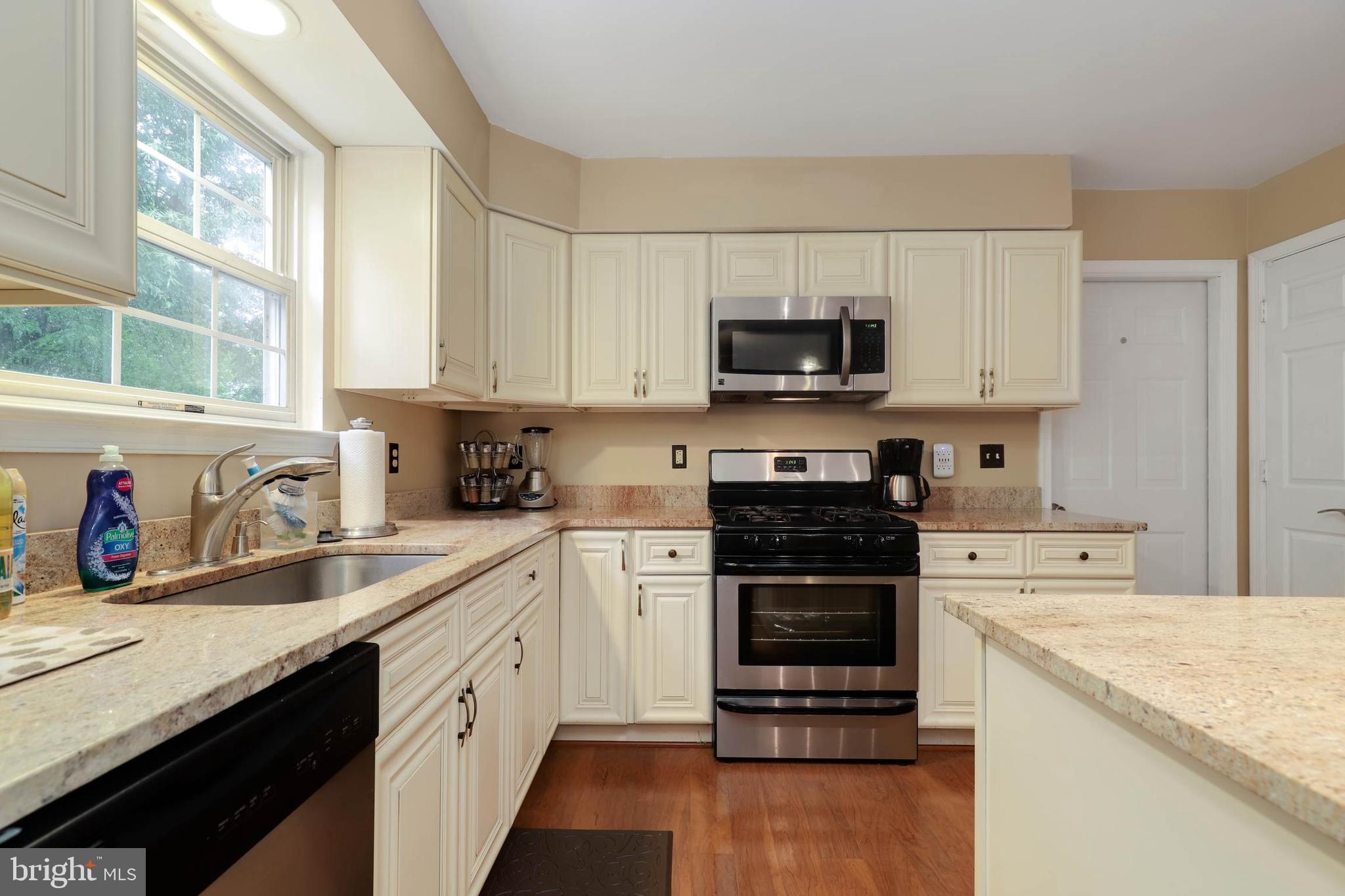 9211 Sandy Creek Road Fort Washington, MD 20744 - Photo 15 of 30 a kitchen with stainless steel appliances granite countertop a stove top oven a sink dishwasher and a refrigerator with wooden floor