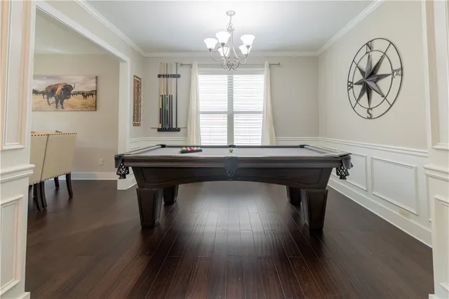 a dining room with wooden floor a chandelier a wooden table and chairs