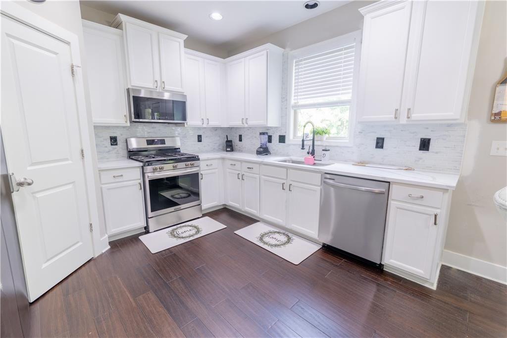 1567 Maplecliff Way Sugar Hill, GA 30518 - Photo 15 of 31 a kitchen with stainless steel appliances a sink dishwasher a stove top oven a refrigerator with white cabinets and wooden floor