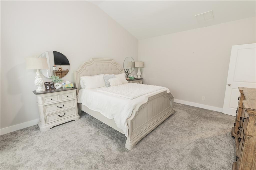 1567 Maplecliff Way Sugar Hill, GA 30518 - Photo 19 of 31 a bedroom with a bed and a flat tv screen on the dresser