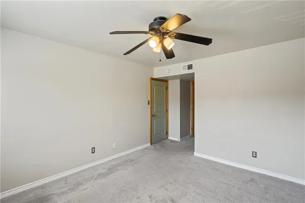 an empty room with closet and a chandelier fan