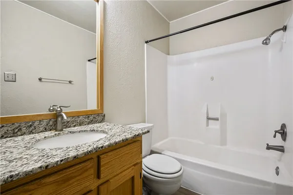 a bathroom with a granite countertop sink toilet and shower