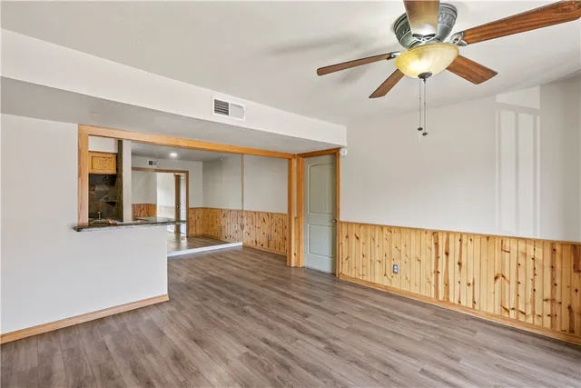 a view of an empty room with window and wooden floor