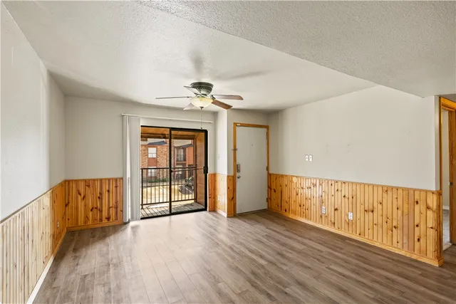 a view of an empty room with wooden floor and windows