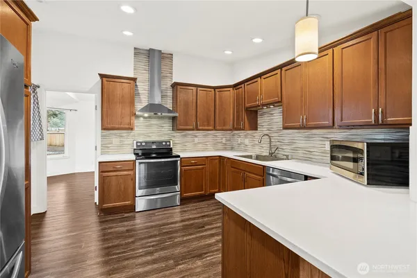 a kitchen with stainless steel appliances kitchen island granite countertop a stove a sink and a refrigerator