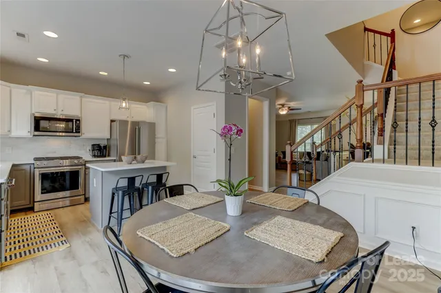 a dining room with wooden floor a chandelier a wooden table and chairs