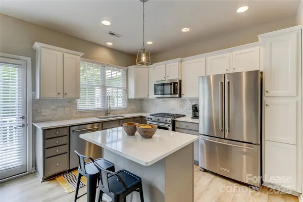 a kitchen with a refrigerator a sink a stove and chairs