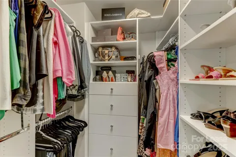 a view of walk in closet with clothes and shoes