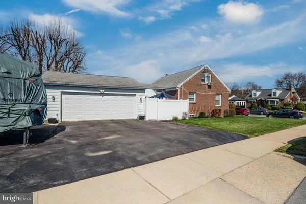 a view of a white house next to a yard with potted plants
