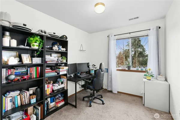 a view of a workspace with bookshelf and a window