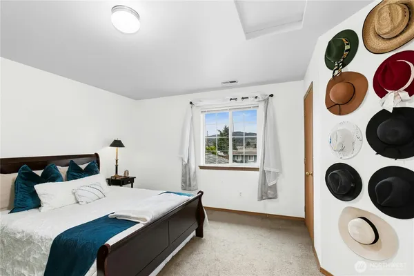 a bedroom with a bed and painting on the wall and dresser