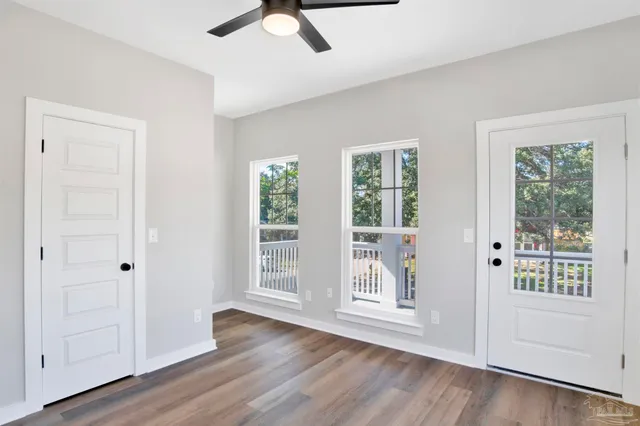 a view of an empty room with wooden floor and a window