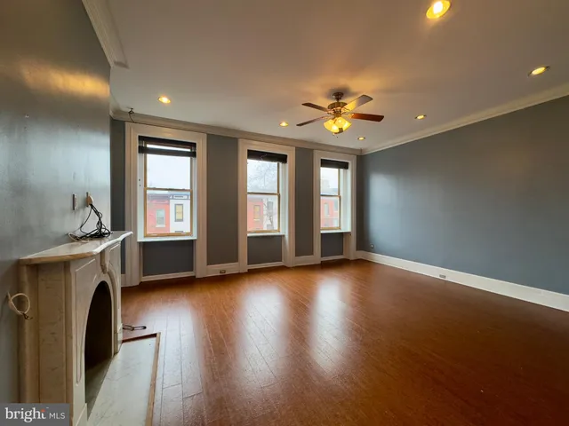 a view of an empty room with window and wooden floor