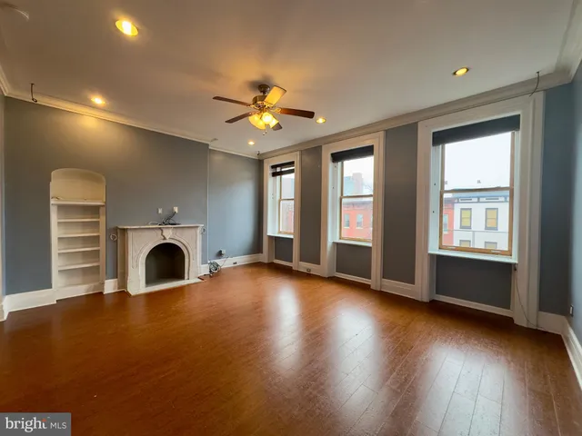 an empty room with windows fireplace and a sink