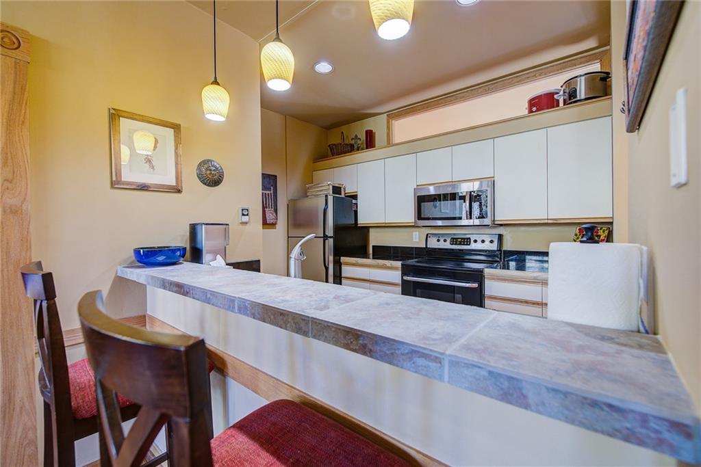 2027 Soda Ridge Road, Unit 1934 Keystone, CO 80435 - Photo 12 of 21 a kitchen with stainless steel appliances granite countertop a stove top oven a sink a dining table and chairs with wooden floor