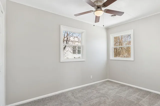 an empty room with a window and a fan