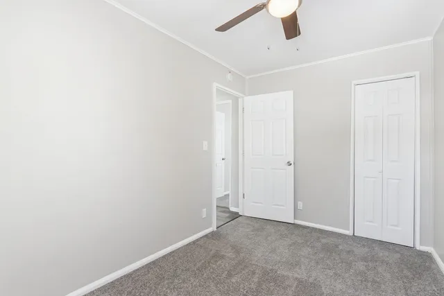 an empty room with a ceiling fan and carpet