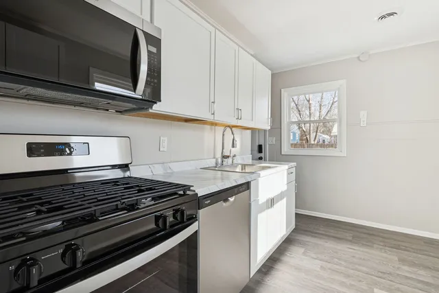 a kitchen with stainless steel appliances granite countertop white cabinets and stove