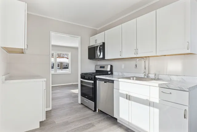 a kitchen with stainless steel appliances granite countertop a stove and white cabinets