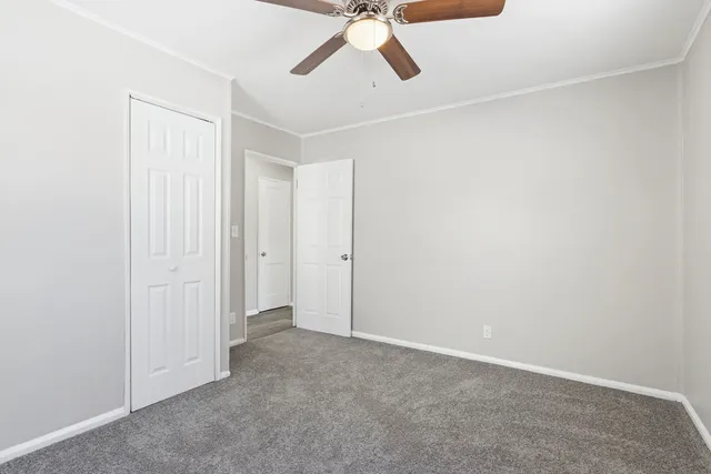 an empty room with a ceiling fan and carpet