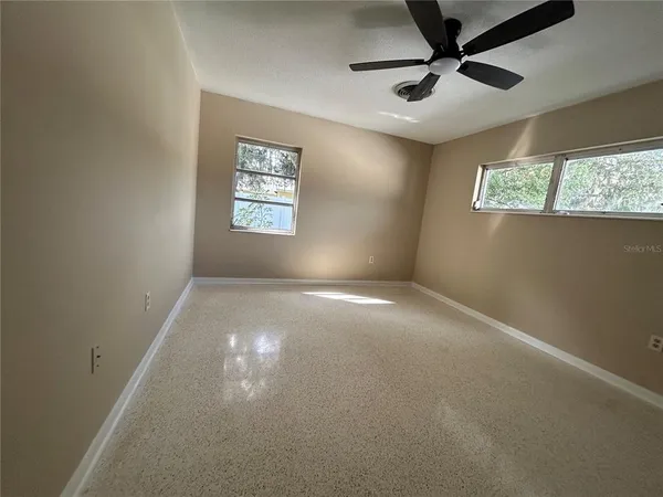 en empty room with windows and ceiling fan