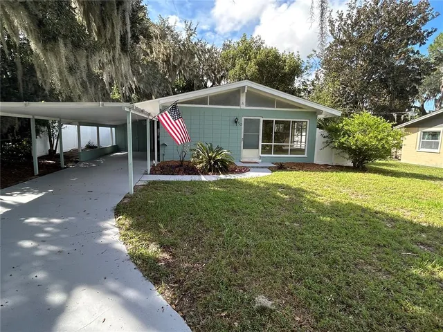 a front view of house with yard and trees in the background