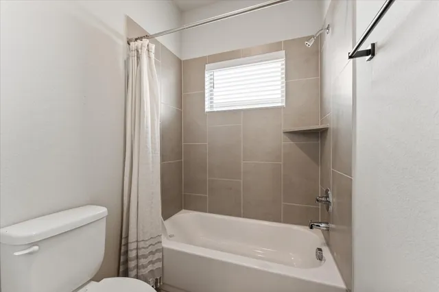 a view of a bathroom with a tub shower and toilet