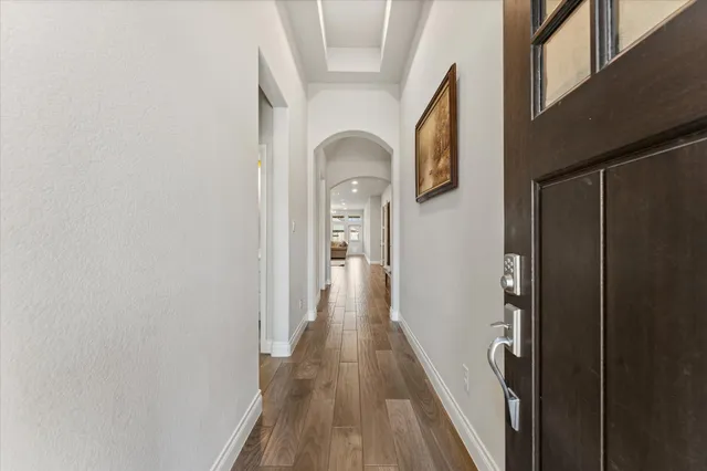 a view of a hallway with wooden floor and a bathroom