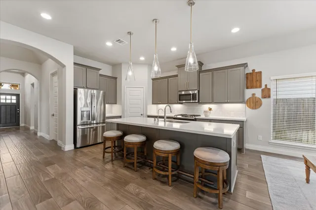 a kitchen with kitchen island a dining table chairs stainless steel appliances and cabinets