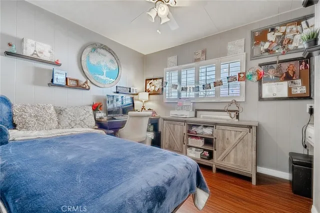 a bedroom with a bed a desk and painting on the wall