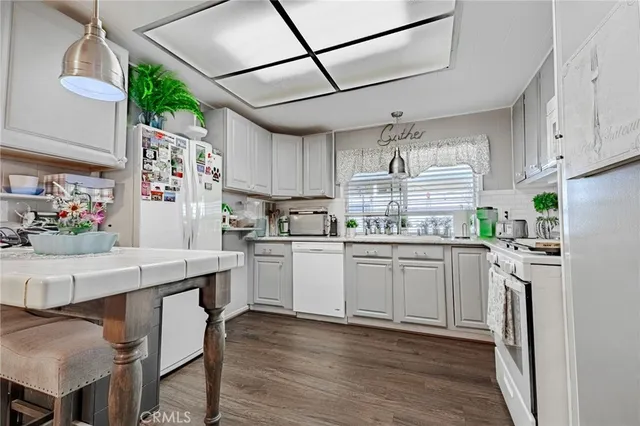 a kitchen with stainless steel appliances a stove a sink dishwasher a refrigerator white cabinets and wooden floor