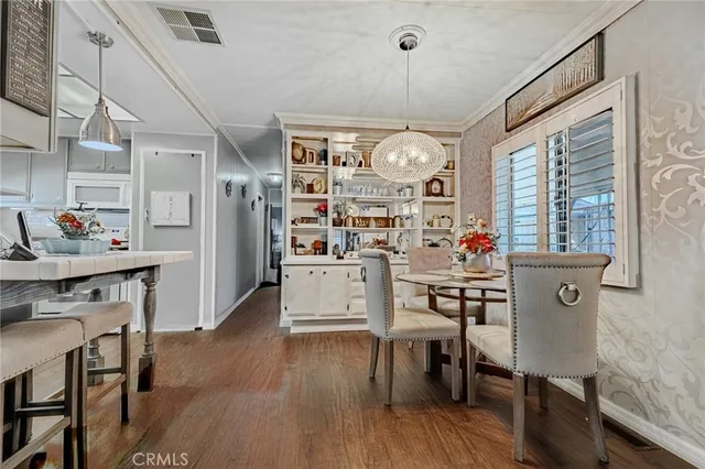a view of a dining room and livingroom with furniture wooden floor a rug a painting and a chandelier