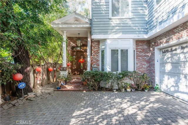 a view of a house with potted plants and a large tree